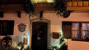 Ein Gebäude mit einem Schild, auf dem 'Osthaus' steht, einer Holztür und Weihnachtsdekorationen, darunter ein Kranz und Lichter.
