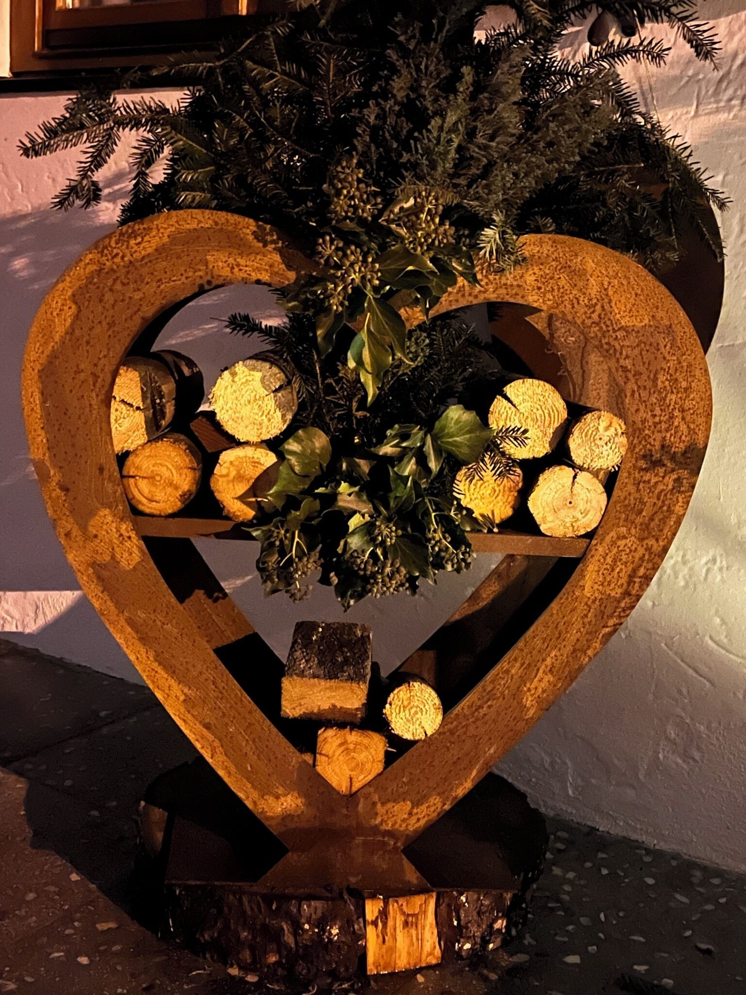 A heart-shaped wooden structure with logs and greenery.