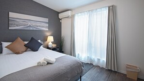 A neatly made bed with pillows, a bedside lamp, and a view of a road through a window. - Travel time Koji Higashi 4LDK Max8ppl (Osaka)