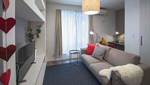 A modern living room with a flat-screen TV, a sofa, a coffee table, and a hanging light fixture. - Travel time Koji Higashi 4LDK Max8ppl (Osaka)