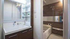 A modern bathroom with a large mirror, a white sink with a faucet, and a shower area with a glass door. - Travel time Koji Higashi 4LDK Max8ppl (Osaka)