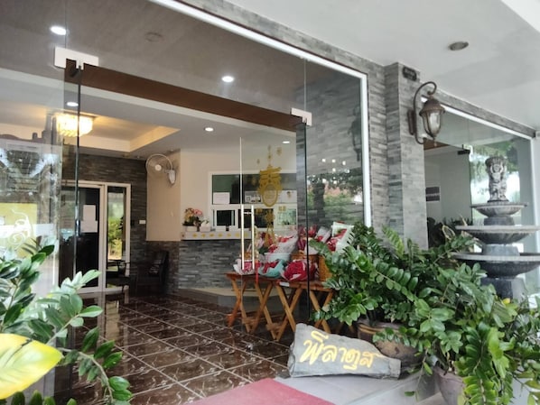 Un interior moderno con mostrador de recepción, pared de piedra y una fuente.