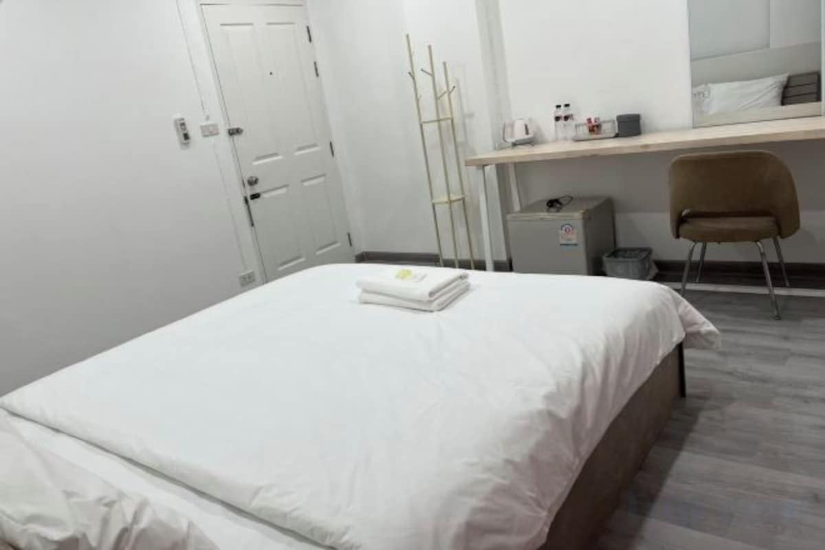 A hotel room with a bed, a desk, a chair, and a wardrobe.