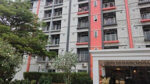 A multi-story building with balconies, a sign reading "PILATUS", and a landscaped entrance area. - Pilatus Apartment (Mueang Loei)