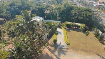 Vista aérea de un área residencial con un camino pavimentado que conduce a una casa rodeada de abundante vegetación y palmeras.