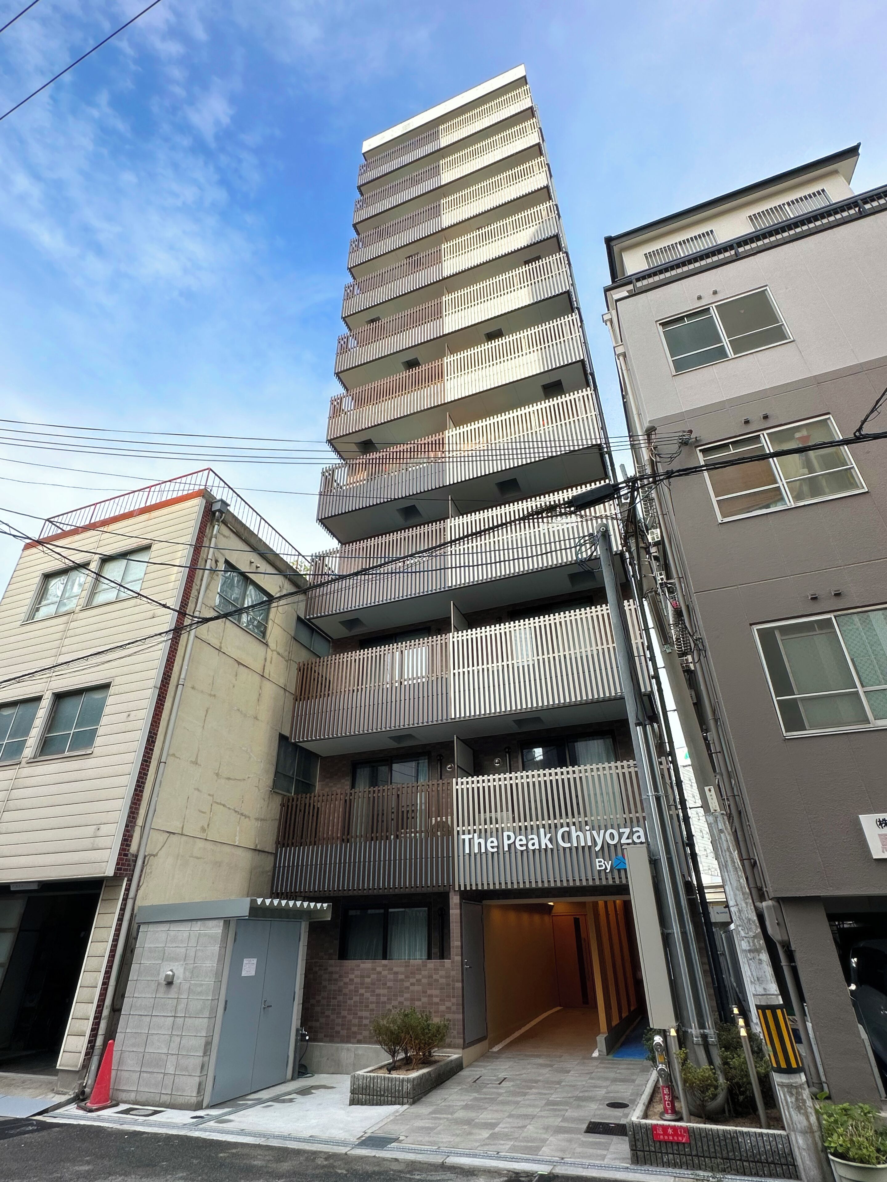 A multi-story building with a modern design, featuring balconies and a gated entrance.