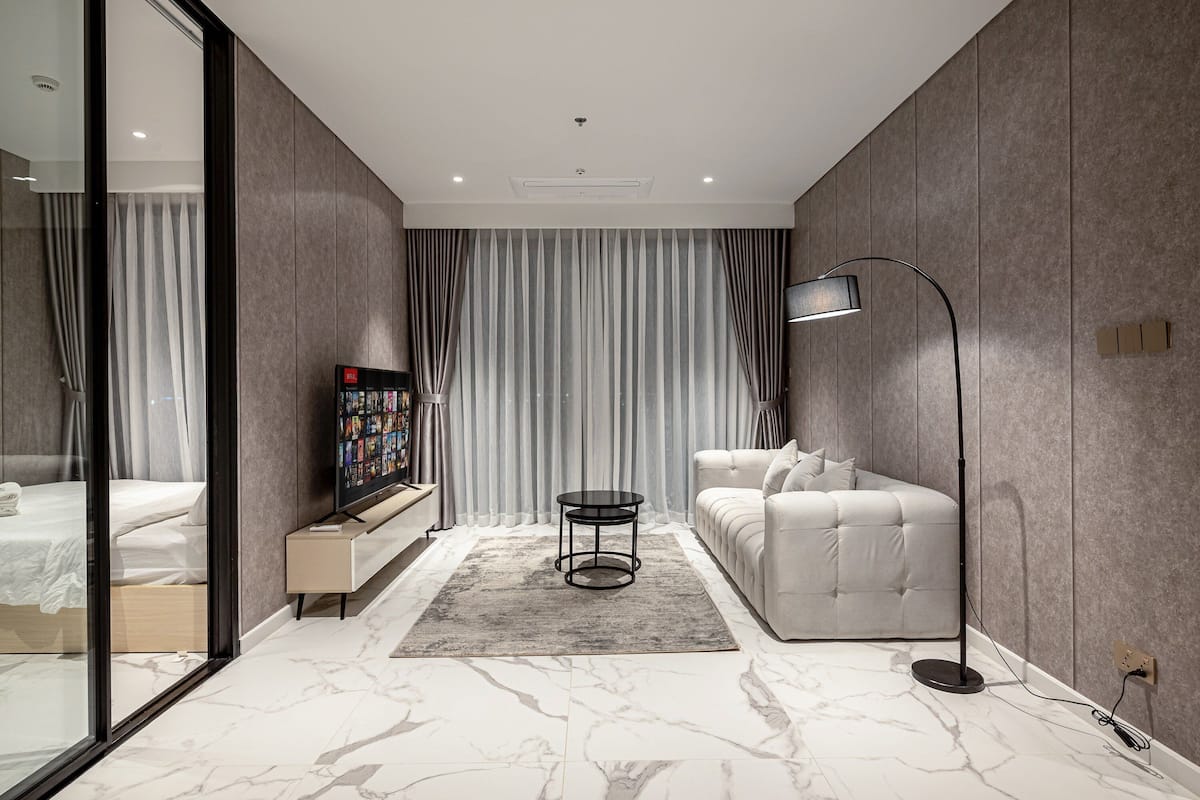 A modern bedroom with a bed, a sofa, a TV, and a floor lamp.