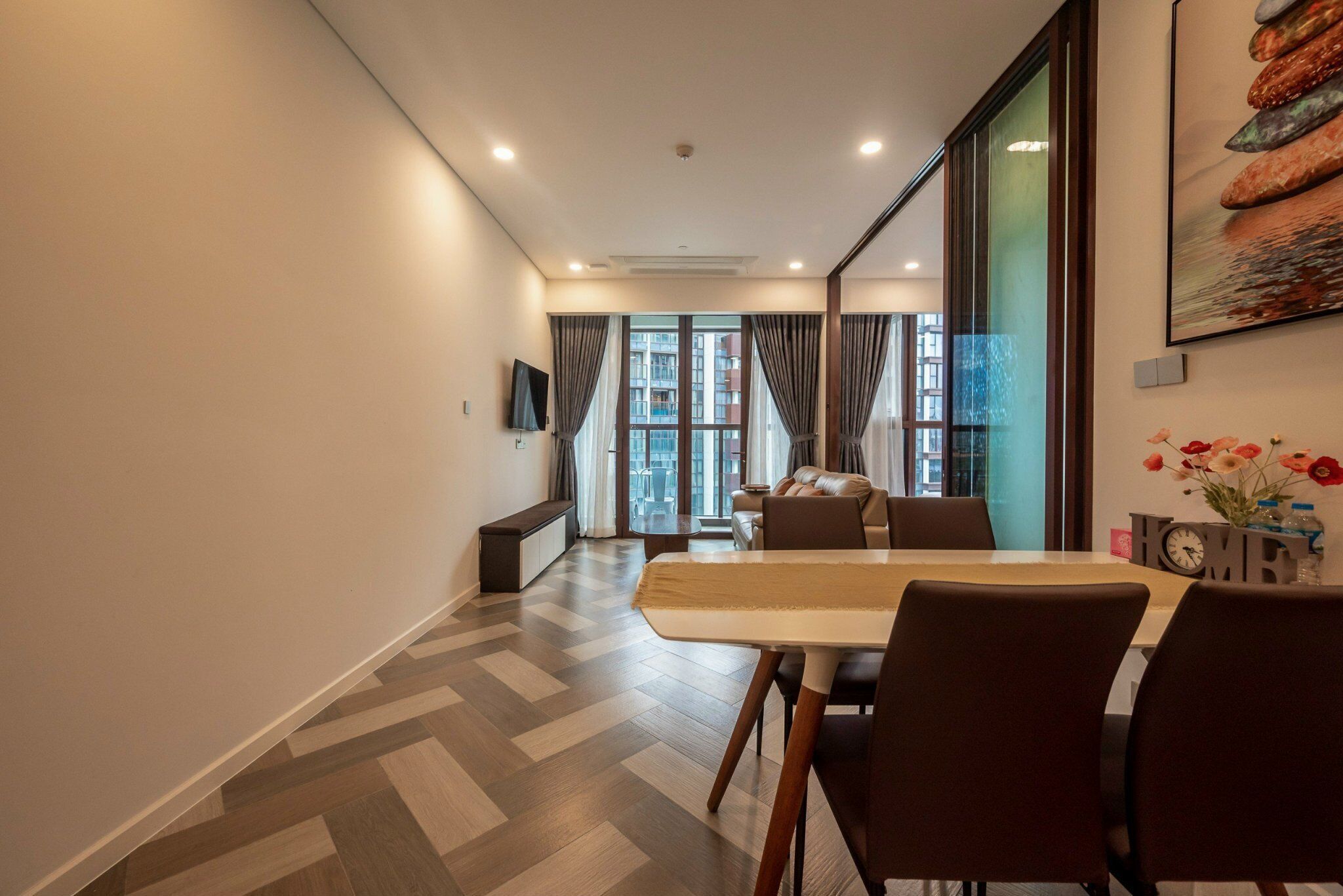 A modern dining area with a herringbone floor pattern, a long table, and several chairs.