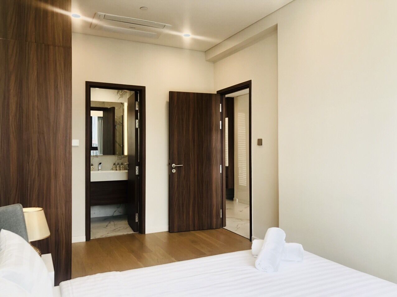 Une chambre d’hôtel comprenant un lit, une table de chevet, un miroir et une porte donnant accès à une salle de bain.
