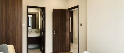 Une chambre d’hôtel comprenant un lit, une table de chevet, un miroir et une porte donnant accès à une salle de bain.