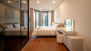 Une chambre d’hôtel moderne avec un grand lit, une table de chevet avec une lampe, un miroir et une vue sur l’extérieur grâce à de grandes fenêtres.
