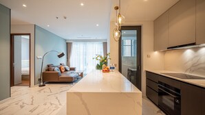 Une cuisine moderne dotée d’un plan de travail en marbre, d’un four encastré et d’un coin repas avec un canapé et une lampe sur pied.
