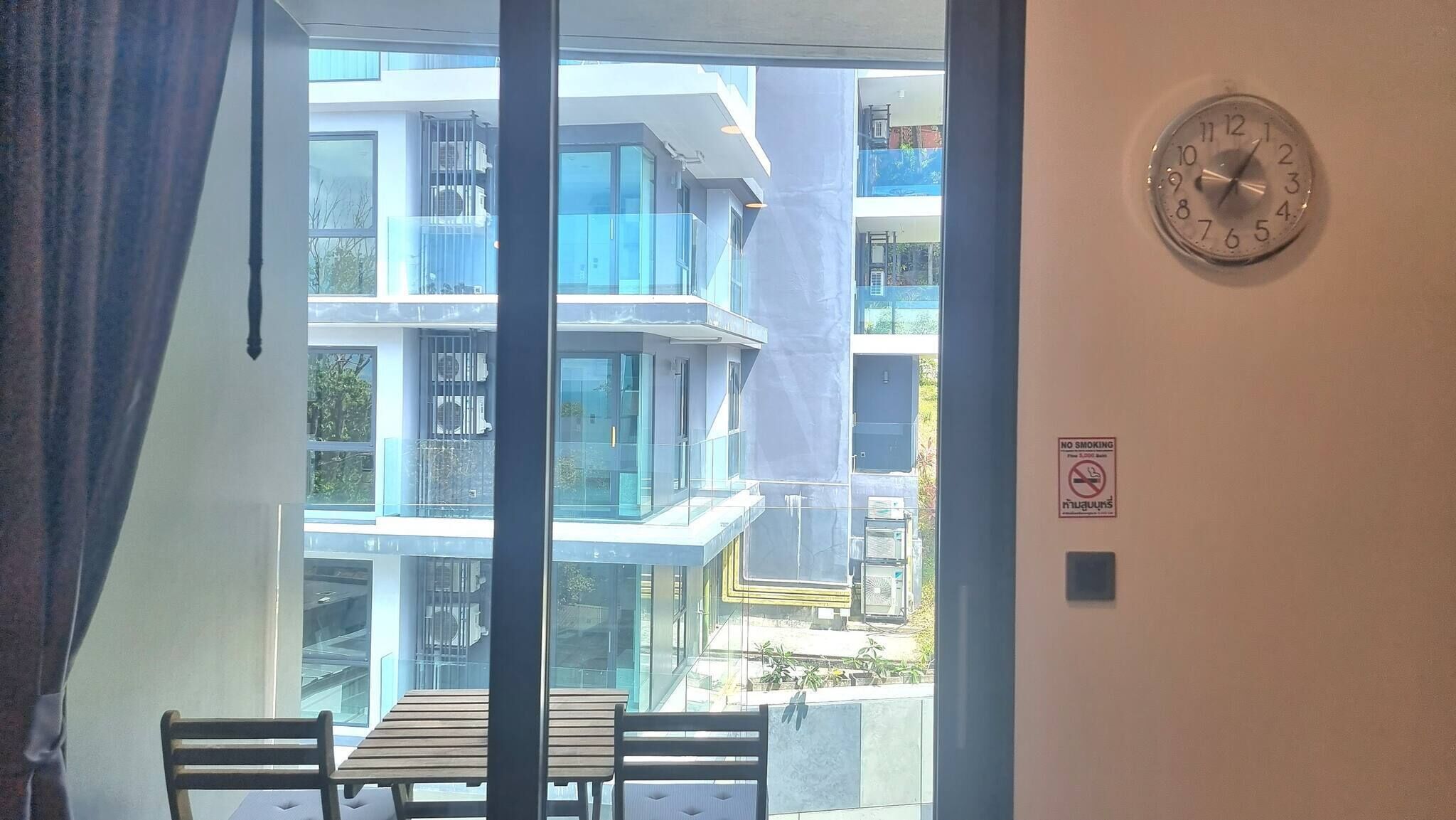 A balcony with a table and chairs, a clock on the wall, and a no smoking sign.