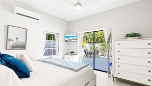 A bedroom with a bed, a dresser, a television, and a view of the outdoors. - Siesta Key Village, Pool, Beach Access 4-min. Walk, 1bdr (Siesta Key)