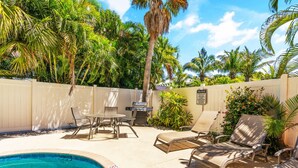 A pool area with lounge chairs, a table, and a grill. - Siesta Key Village, Pool, Beach Access 4-min. Walk, 1bdr (Siesta Key)
