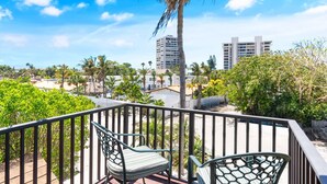 A balcony with two chairs, overlooking a residential area with palm trees and buildings. - Siesta Key Village, Pool, Beach Access 4-min. Walk, 3bdr (Siesta Key)