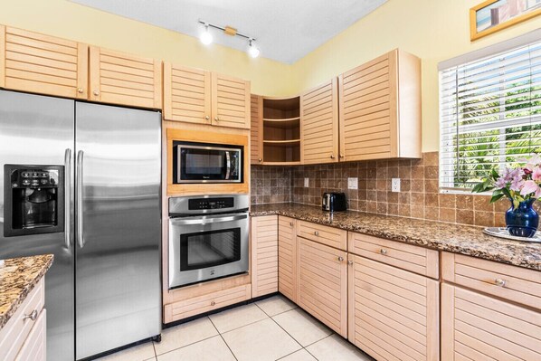 A kitchen with wooden cabinets, stainless steel appliances, and a tiled backsplash.