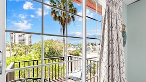 A balcony with a view of palm trees and buildings, a patterned curtain, and a chair. - Siesta Key Village, Pool, Beach Access 4-min. Walk, 3bdr (Siesta Key)