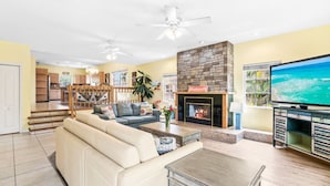 A spacious living room with a fireplace, a television, and a dining area in the background. - Siesta Key Village, Pool, Beach Access 4-min. Walk, 3bdr (Siesta Key)