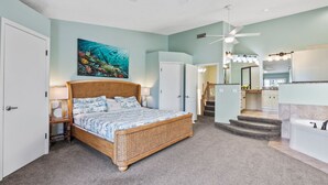 A bedroom with a bed, a ceiling fan, a bathroom with a sink and mirror, and a staircase leading to another room. - Siesta Key Village, Pool, Beach Access 4-min. Walk, 3bdr (Siesta Key)