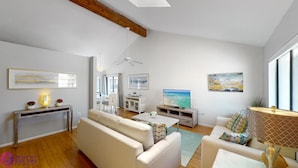 A modern living room with a sofa set, a coffee table, a TV, and artwork on the walls.