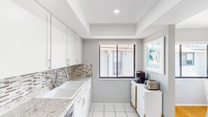 A modern kitchen with white cabinets, a granite countertop, and a window with a view of the outside. - Beach Rd, 300ft to Beach Access & 500ft to Siesta Key Village, 2bdr (Siesta Key)
