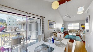 A spacious living area with a balcony, a dining area, and a seating area with a sofa and coffee table.