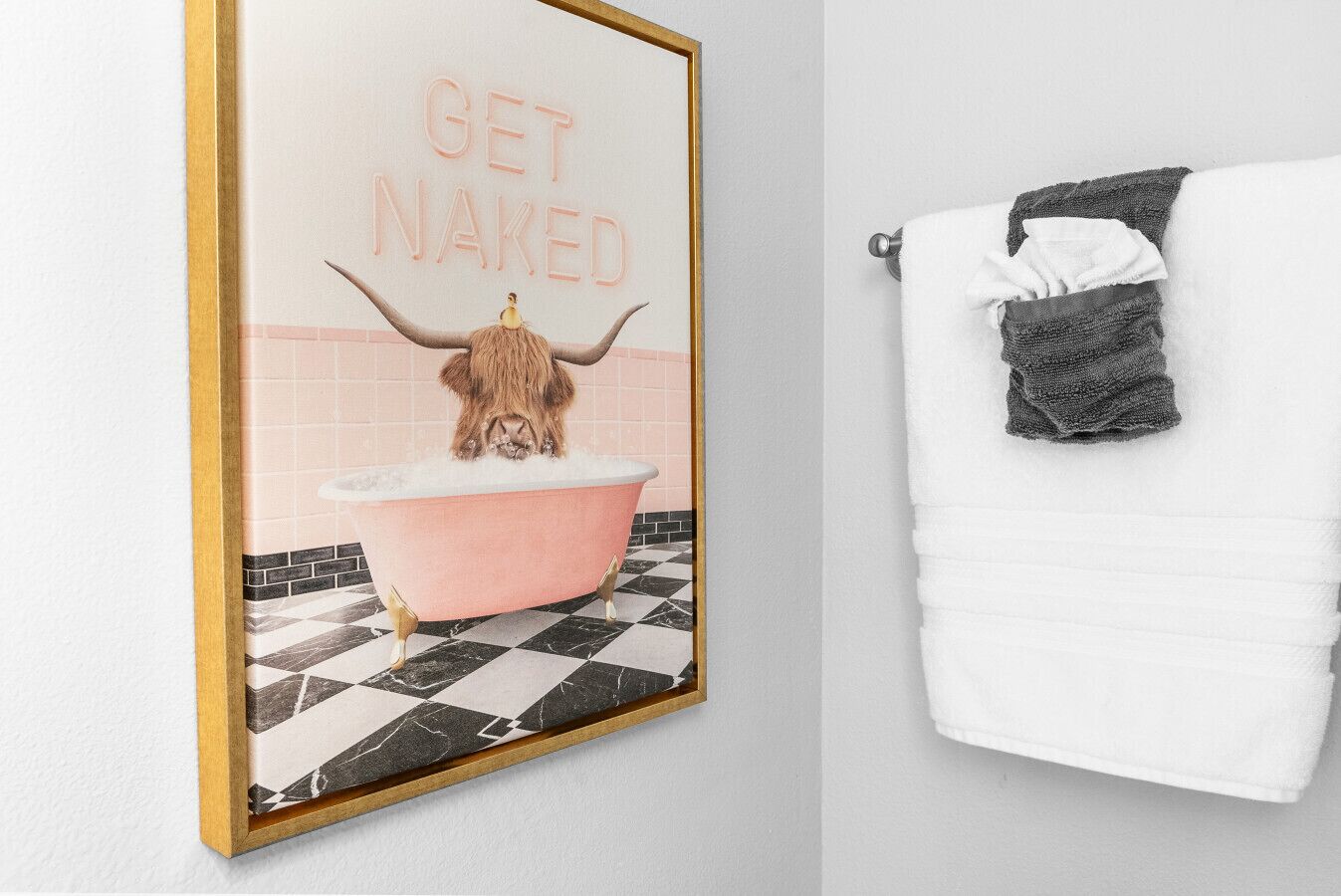 Um banheiro com uma banheira rosa, um porta-toalhas com uma toalha branca e um pôster com um touro e o texto "GET NAKED".