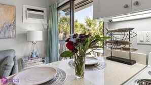 A modern kitchen with a dining area, a vase of flowers, and a view of palm trees outside. - Beach Rd, 300ft to Beach Access & 500ft to Siesta Key Village, Studio (Siesta Key)