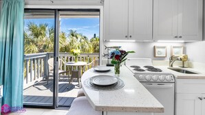 A kitchen with a large window, a dining area with a table and chairs, and a view of palm trees outside. - Beach Rd, 300ft to Beach Access & 500ft to Siesta Key Village, Studio (Siesta Key)