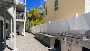 Eine Terrassenausstattung mit Grill, Stauraumschränken und einem weißen Zaun.
