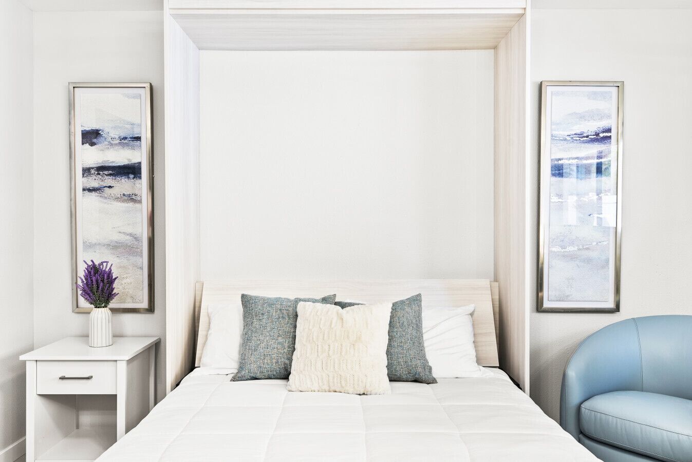 A modern bedroom with a bed, bedside tables, and artwork on the walls.