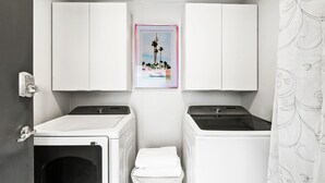 Une buanderie équipée de deux machines à laver, d’un sèche-linge et d’un petit panier contenant une serviette.