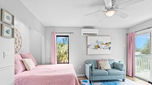 Une chambre à coucher avec un lit, un canapé, une grande fenêtre et un ventilateur de plafond.