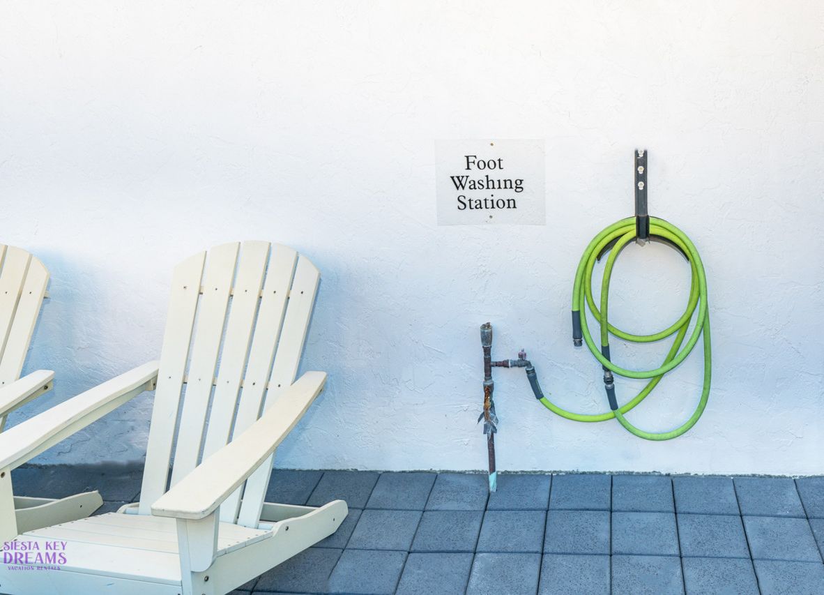 A foot washing station with a hose and a chair.