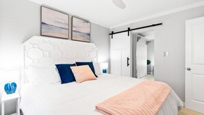 A modern bedroom with a white bed, blue and peach pillows, a white headboard, and a ceiling fan. - Beach Rd, 300ft to Beach Access & 500ft to Siesta Key Village, 1bdr (Siesta Key)