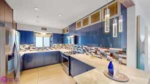 Una cocina moderna con gabinetes azules, una isla central y una barra desayunadora.