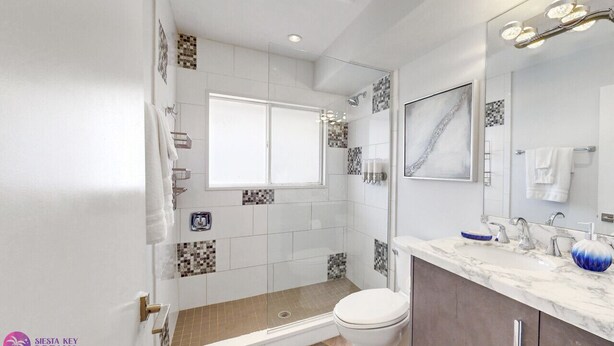 A modern bathroom with a shower, toilet, and sink.