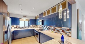 Una cocina moderna con gabinetes azules, una isla central y una barra desayunadora.