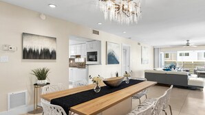 Une cuisine moderne avec des meubles blancs, un îlot central en bois et un lustre.