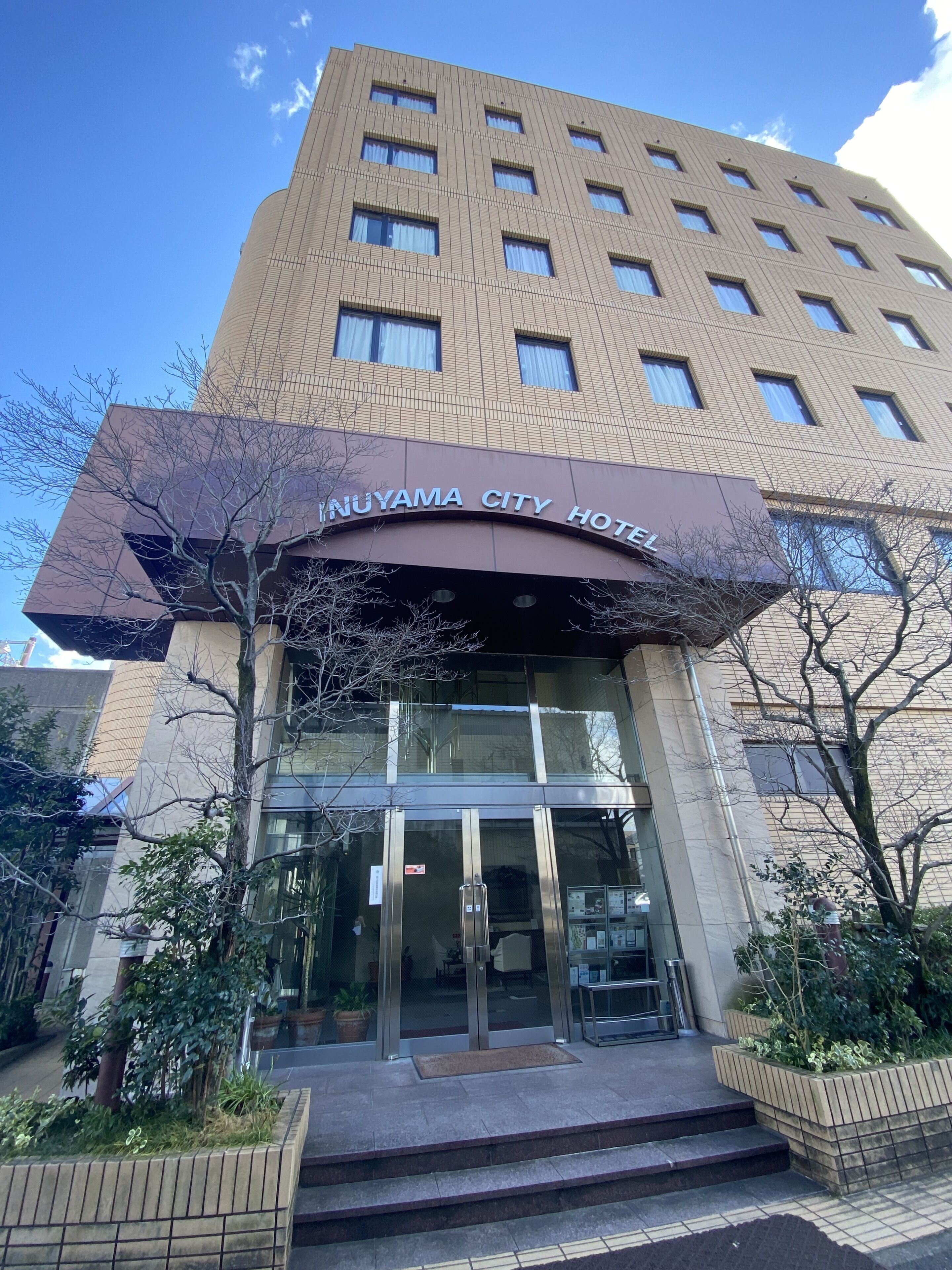 The entrance to Nuyama City Hotel with a modern design, featuring a glass facade and a prominent entrance canopy.