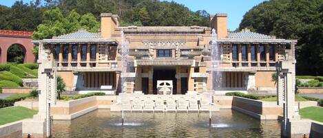 A traditional building with a central entrance, flanked by two wings, and a water feature in front.