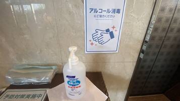 Una botella de gel hidroalcohólico sobre una mesa con un letrero que indica desinfectar las manos con alcohol.