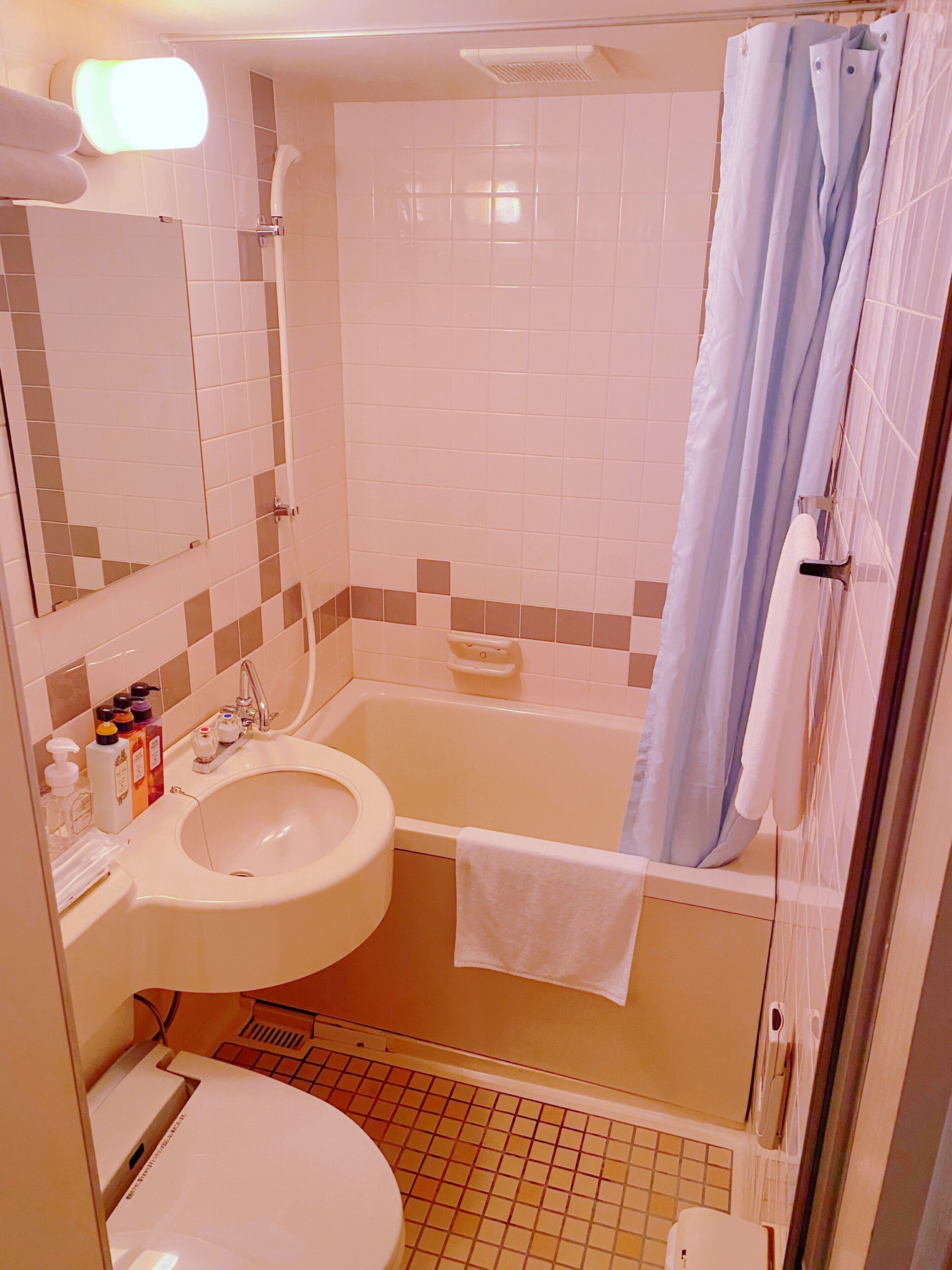 A bathroom with a sink, toilet, bathtub, and a shower curtain.