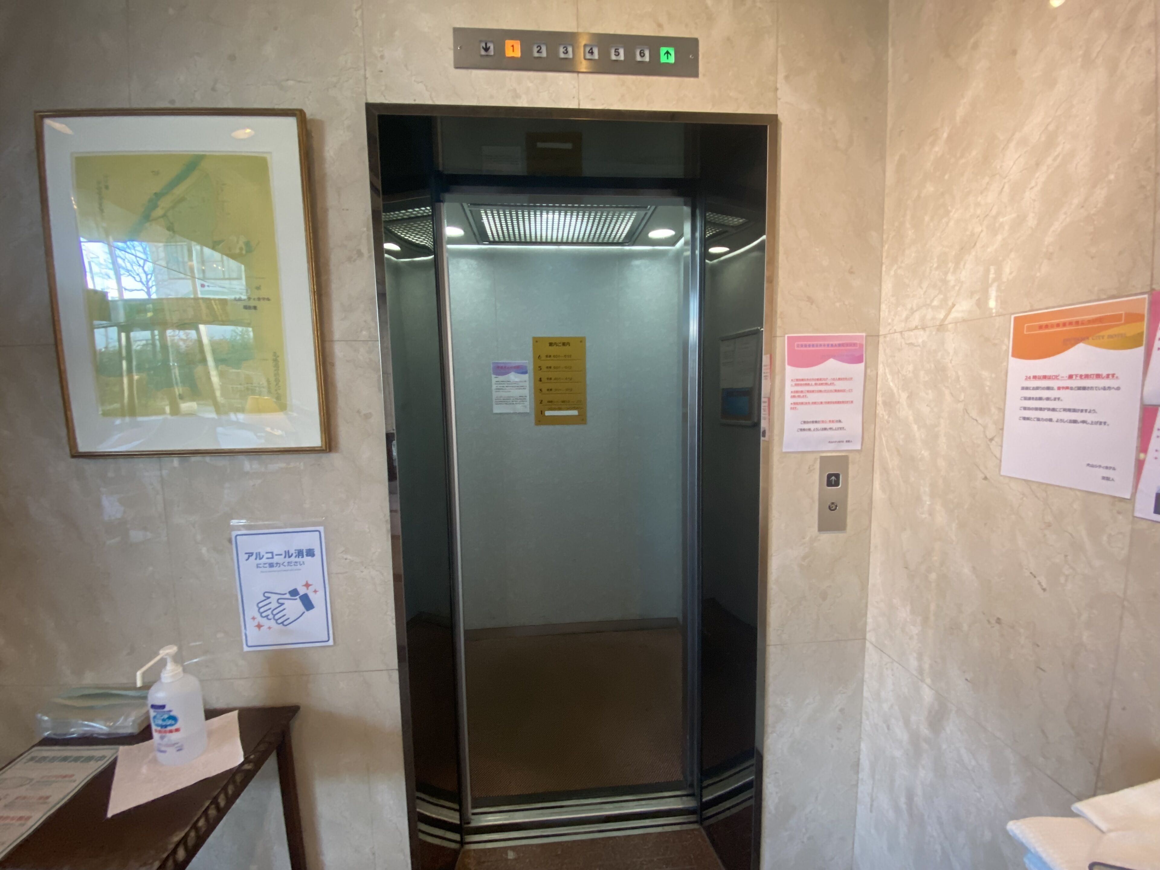Um elevador com visor digital exibindo números de andar e uma seta para cima indicando a direção.