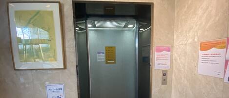 Um elevador com visor digital exibindo números de andar e uma seta para cima indicando a direção.