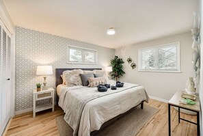 A bedroom with a bed, bedside tables, a nightstand, a potted plant, and a window with blinds. - Château des Fleur-Min to Wash Park & DT Denver (Denver)