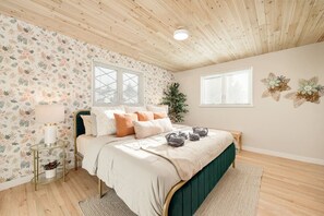 A bedroom with a bed, a bedside table with a lamp, a window, and a wall with floral wallpaper. - Château des Fleur-Min to Wash Park & DT Denver (Denver)