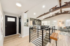 A modern interior with a kitchen, dining area, and living space, featuring a staircase with a metal railing and a bench. - Château des Fleur-Min to Wash Park & DT Denver (Denver)