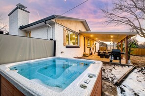 Una casa moderna con jacuzzi, un porche cubierto y una terraza de madera.